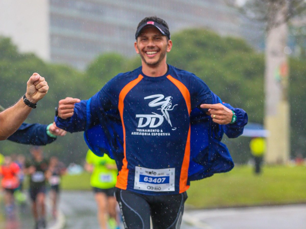 Atleta da DD Treinamento comemorando ao cruzar a linha de chegada, com a camisa da equipe